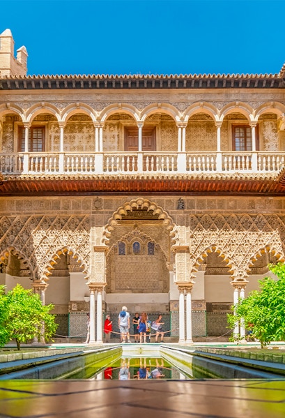Courtyard with intricate arches and reflecting pool at Alcazar of Seville.