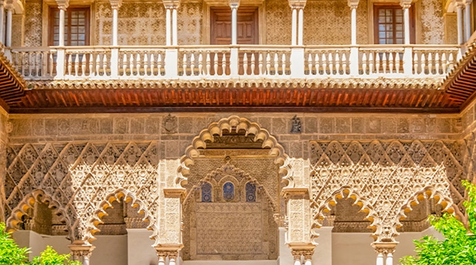 Courtyard with intricate arches and reflecting pool at Alcazar of Seville.