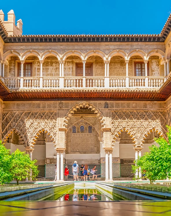 Courtyard with intricate arches and reflecting pool at Alcazar of Seville.