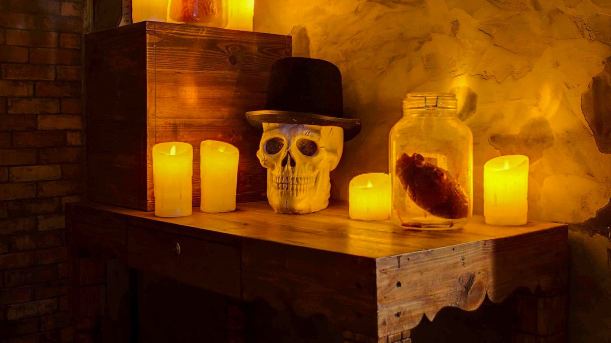 Skull with hat and candles on a wooden table in Jack The Ripper Escape Room, Dubai.