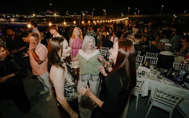 Guests enjoying New Year's Eve on a Marina Dhow dinner cruise, with festive lights and drinks.