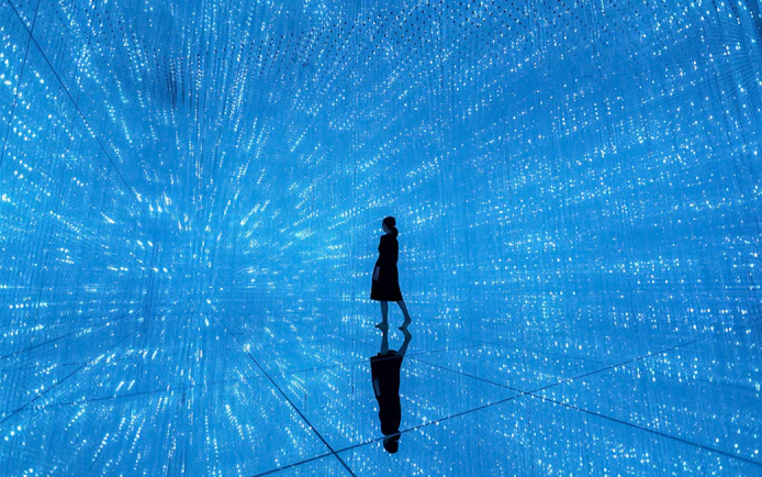 Silhouette in blue digital art installation at TeamLab Planets Tokyo.
