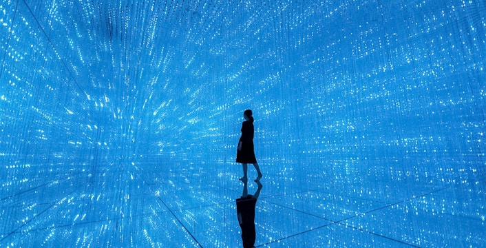 Silhouette in blue digital art installation at TeamLab Planets Tokyo.