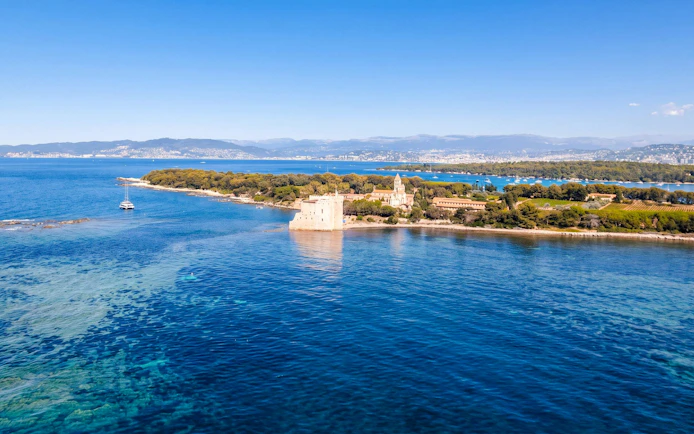 Catamaran near Lérins Island with historic fort and lush landscape, Marina Bay of Angels.