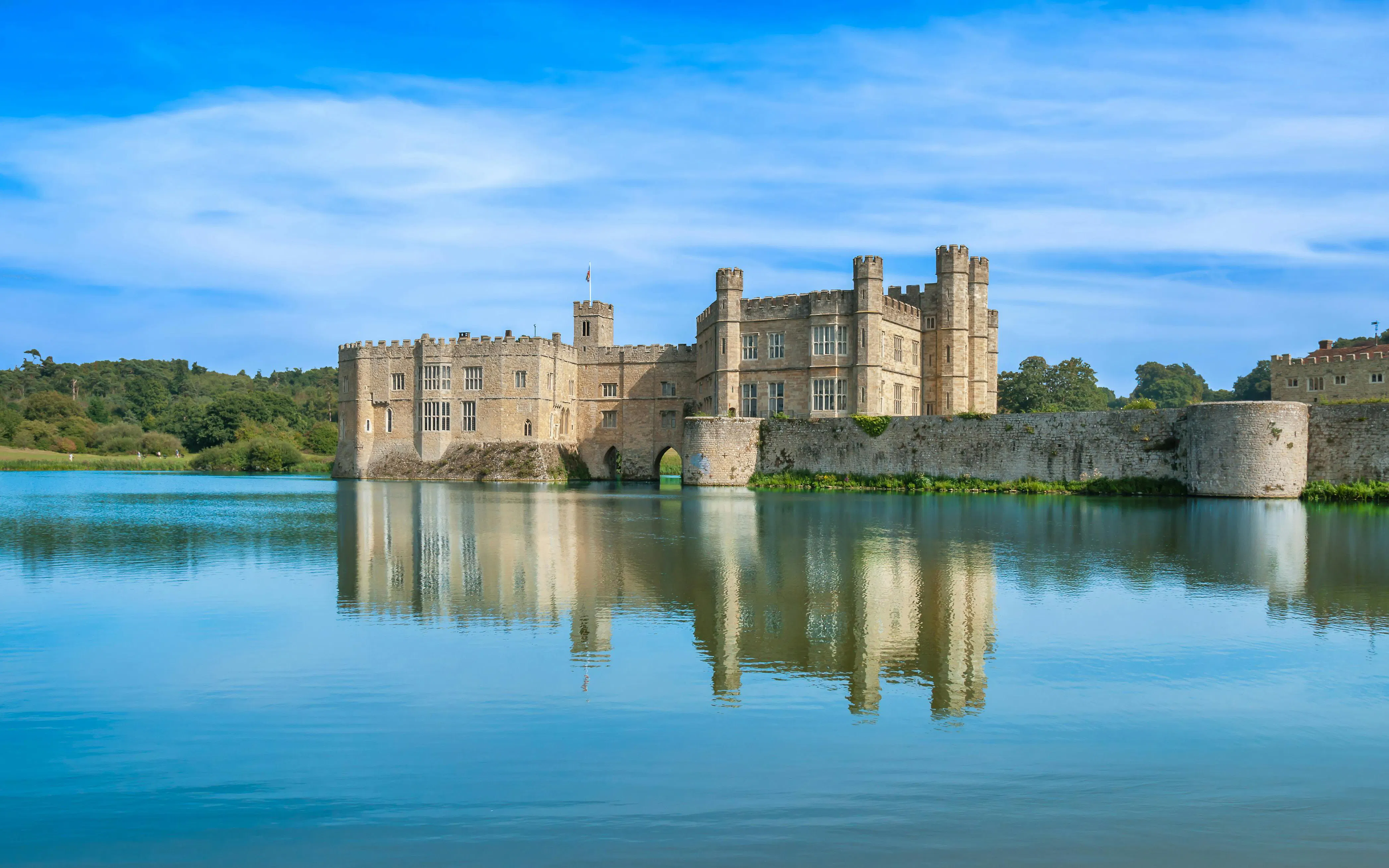 Leeds Castle surrounded by a moat under a clear blue sky.