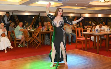 Belly dancer performing on a Cairo Nile dinner cruise with guests dining in the background.