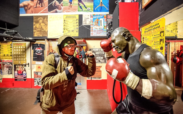 Man posing with boxing statue in St. Pauli museum during Sex & Crime Tour.