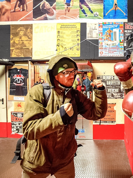 Man posing with boxing statue in St. Pauli museum during Sex & Crime Tour.