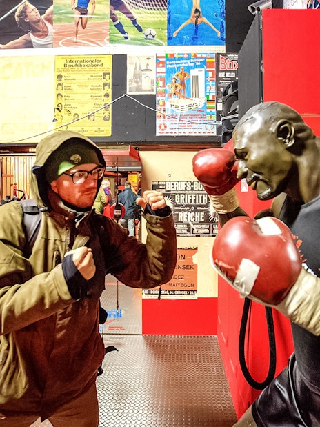 Man posing with boxing statue in St. Pauli museum during Sex & Crime Tour.
