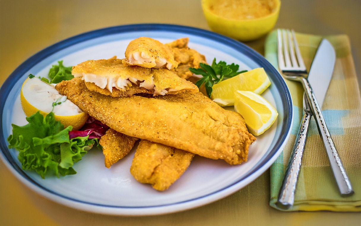 Breaded catfish with lemon wedges on Steamboat Natchez lunch cruise plate.