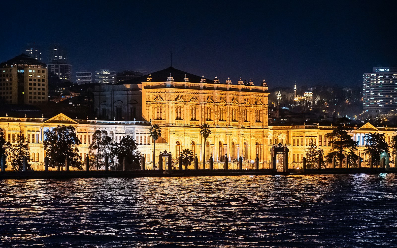 Dolmabahçe Palace exterior view, Istanbul, Turkey, showcasing ornate architecture and Bosphorus backdrop.