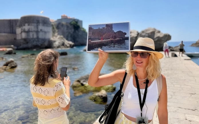 Female guide showing Game of Thrones location to tourists in Dubrovnik, Croatia.