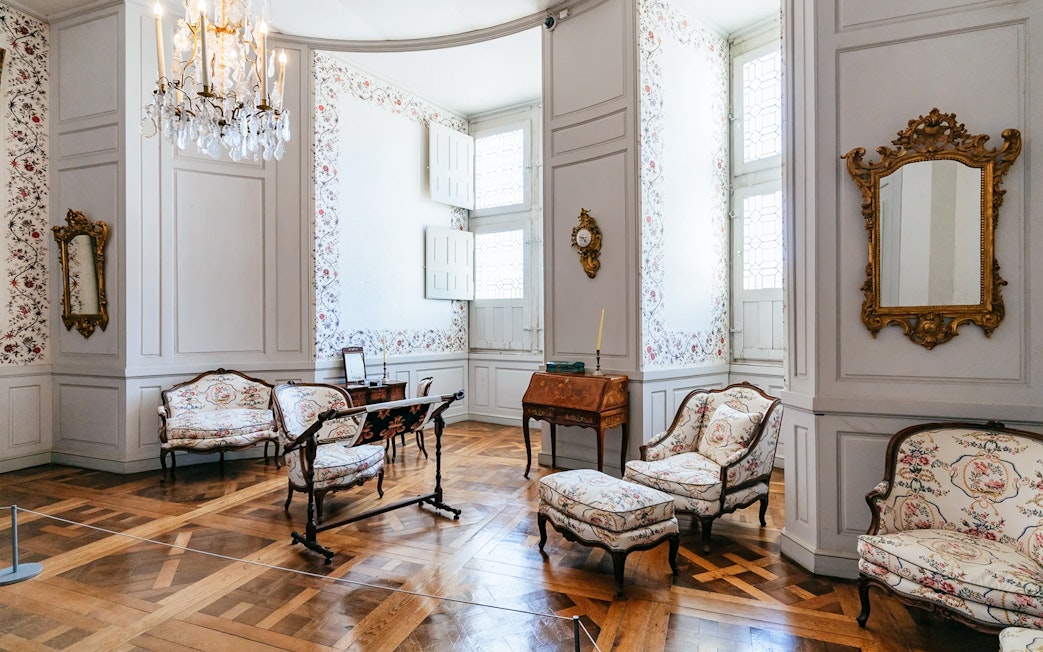 Chambord Castle interior with ornate furniture and floral wallpaper.