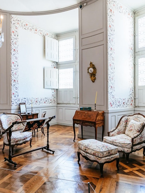 Chambord Castle interior with ornate furniture and floral wallpaper.