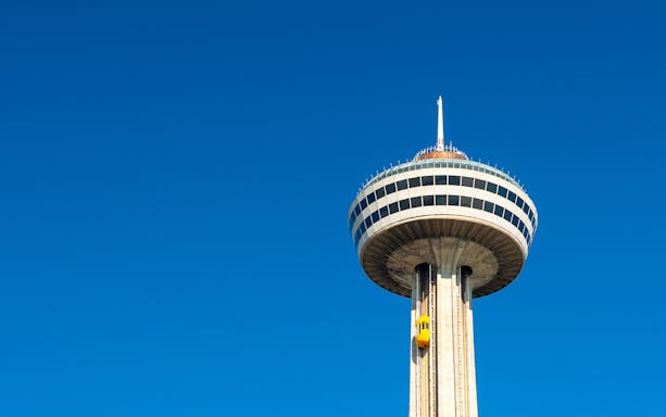 Skylon Tower observation deck with yellow elevator against clear blue sky.