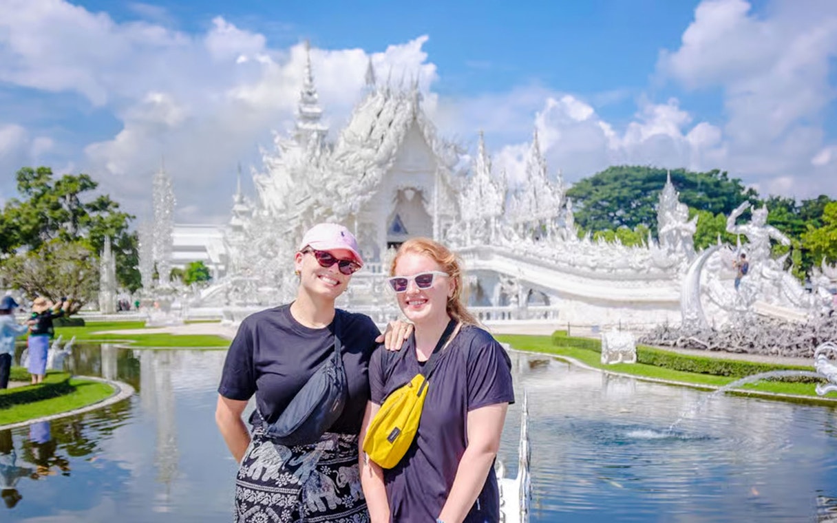 Wat Rong Khun's ornate white exterior with visitors in front, Chiang Rai, Thailand.