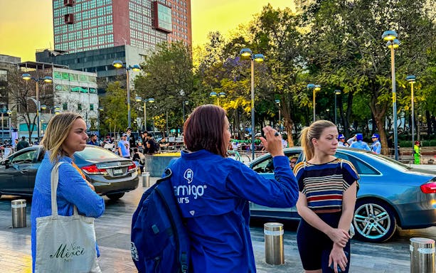 Tour guide leading a group in a city square during a guided night tour.