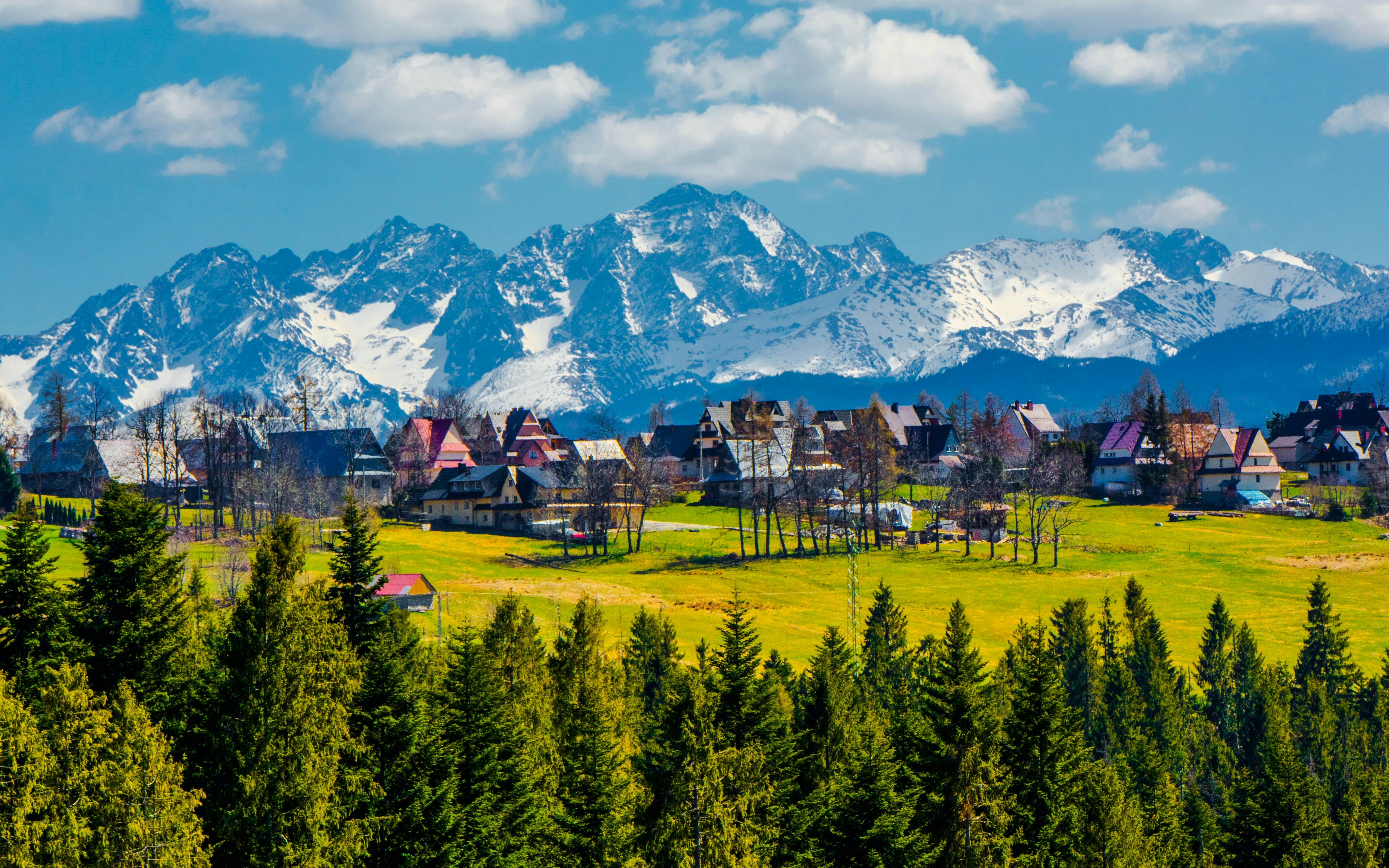Village with traditional houses in front of the Tatra mountain range, Poland.