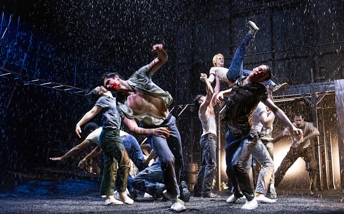 Dancers perform a dramatic scene in the rain from "The Outsiders" stage production.