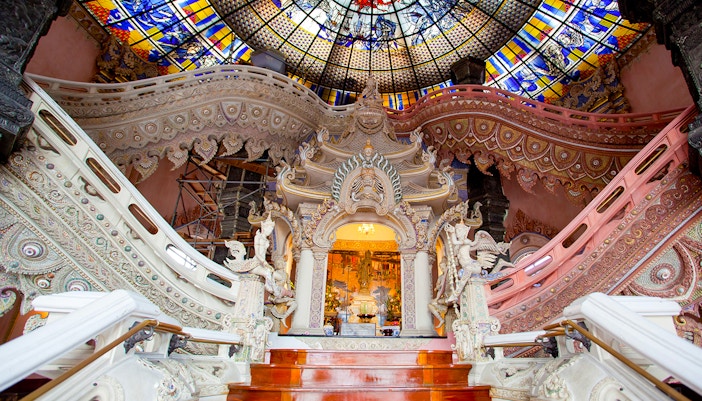 Erawan Museum interior with ornate staircase and stained glass ceiling.