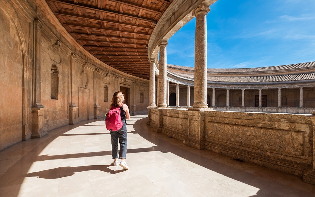 Visitor exploring the circular courtyard of the Alhambra Palace in Granada.