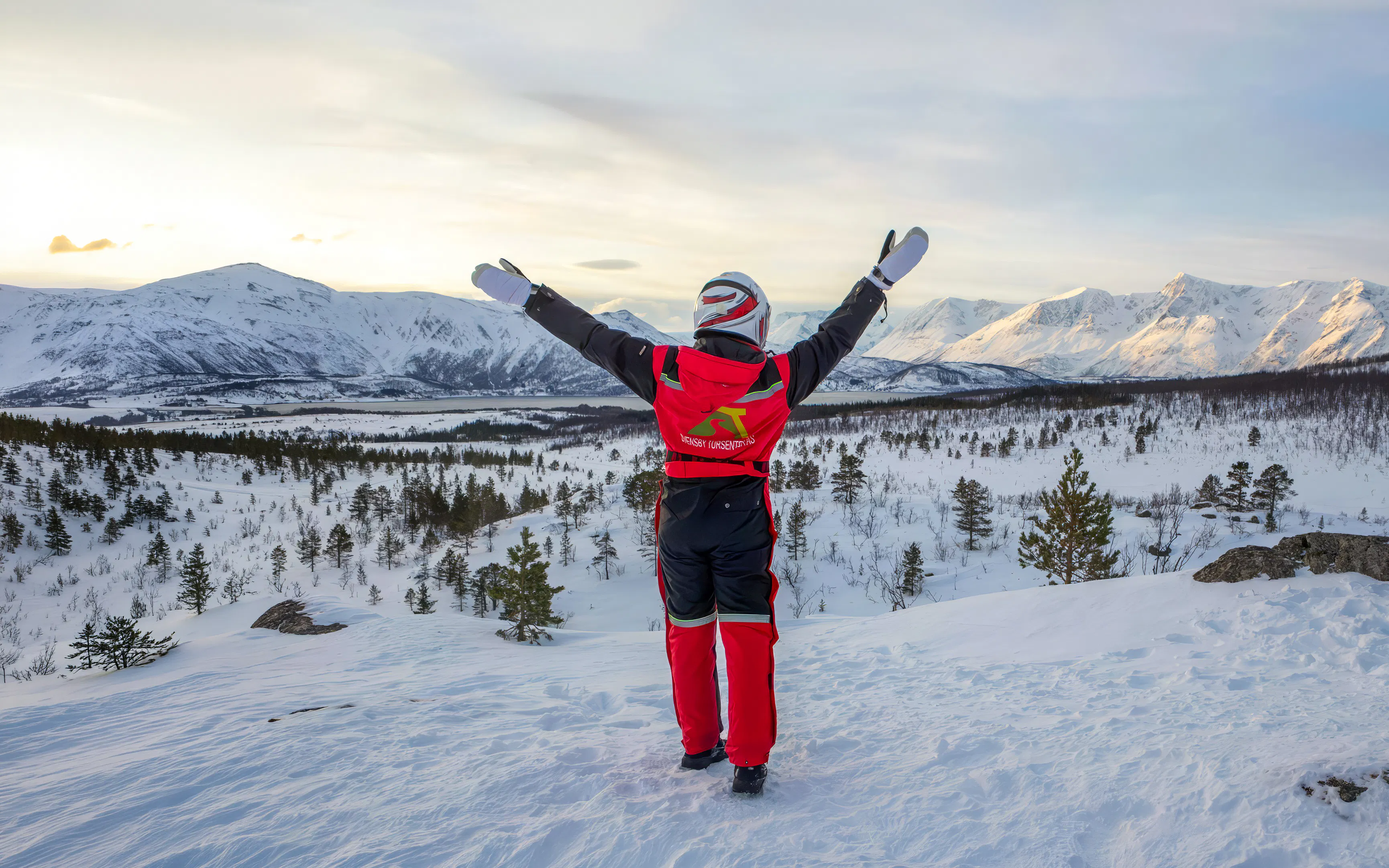 Guest enjoying snowmobile tour in Tromsø's Lyngen Alps with snowy landscape.