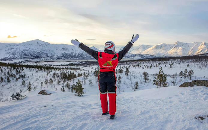 Guest enjoying snowmobile tour in Tromsø's Lyngen Alps with snowy landscape.