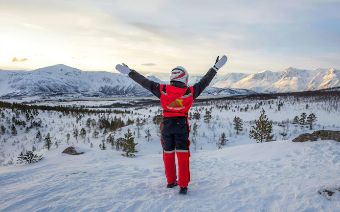 Guest enjoying snowmobile tour in Tromsø's Lyngen Alps with snowy landscape.