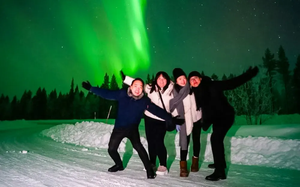 Guests enjoying northern lights during group tour in Rovaniemi.