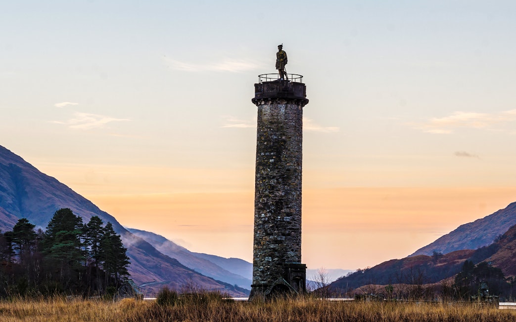 Glenfinnan Monument at sunset with surrounding hills, Scotland.
