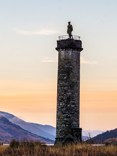 Glenfinnan Monument at sunset with surrounding hills, Scotland.