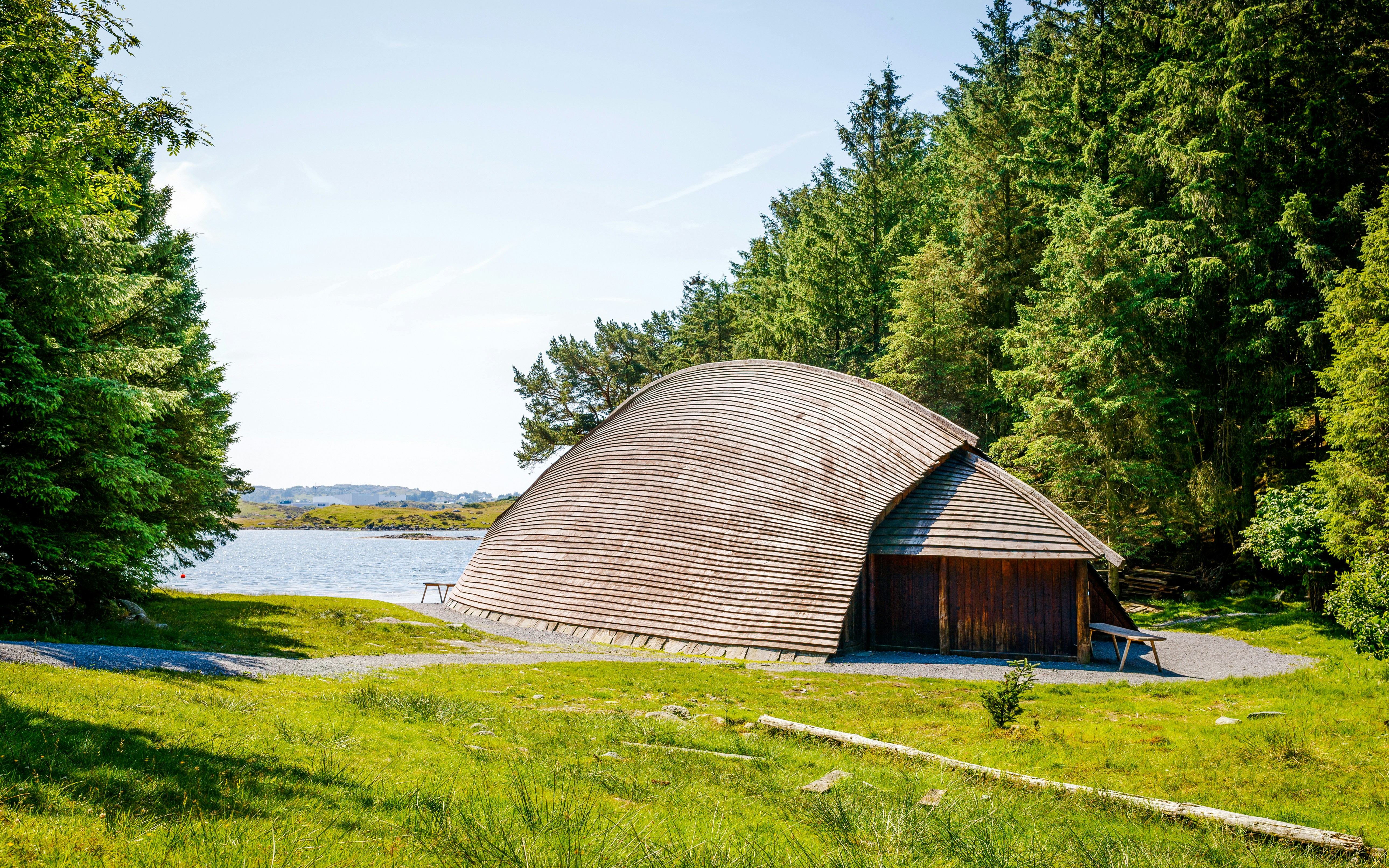 Viking longhouse by the coast in Avaldsnes, Haugesund, Norway, surrounded by trees.