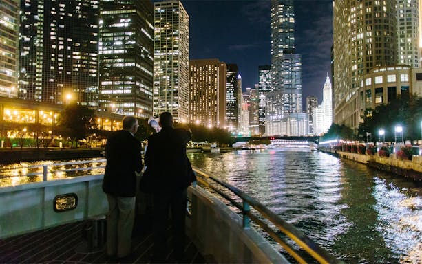Cruise on Chicago River with city skyline at night.