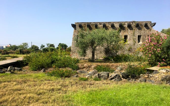 Stone building and garden at Archaeological Museum and Site of Naxos, Greece.