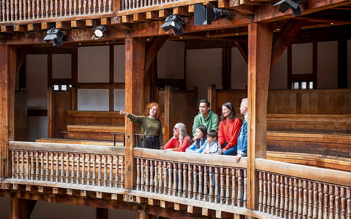 Tour guide explaining Shakespeare's Globe Theatre to visitors on a guided tour.