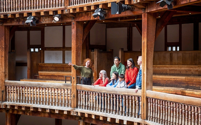 Tour guide explaining Shakespeare's Globe Theatre to visitors on a guided tour.