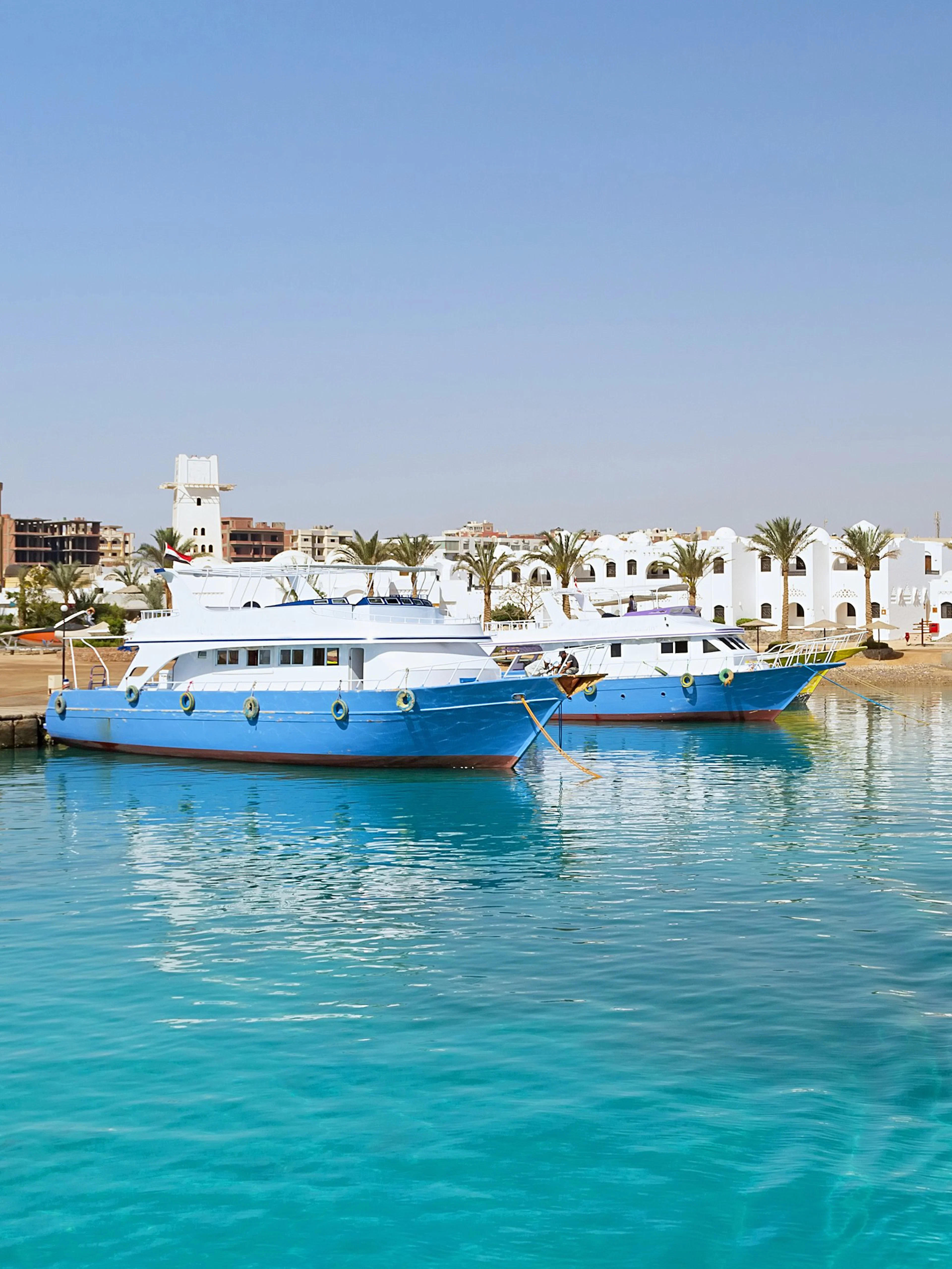 Cruise boats docked at Hurghada harbor with cityscape in the background.