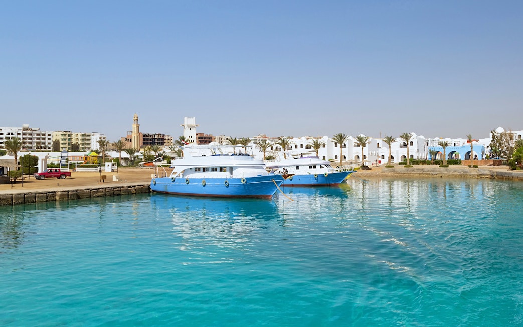Cruise boats docked at Hurghada harbor with cityscape in the background.