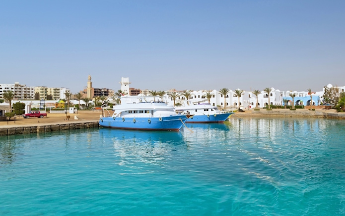 Cruise boats docked at Hurghada harbor with cityscape in the background.