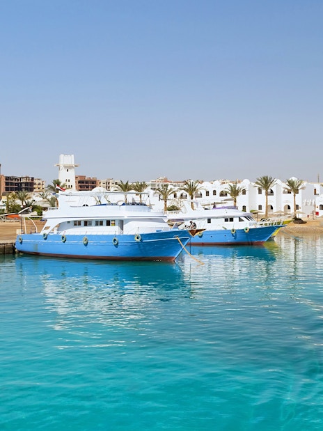 Cruise boats docked at Hurghada harbor with cityscape in the background.