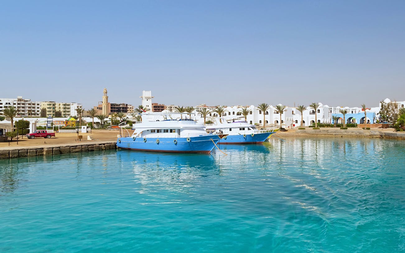 Cruise boats docked at Hurghada harbor with cityscape in the background.