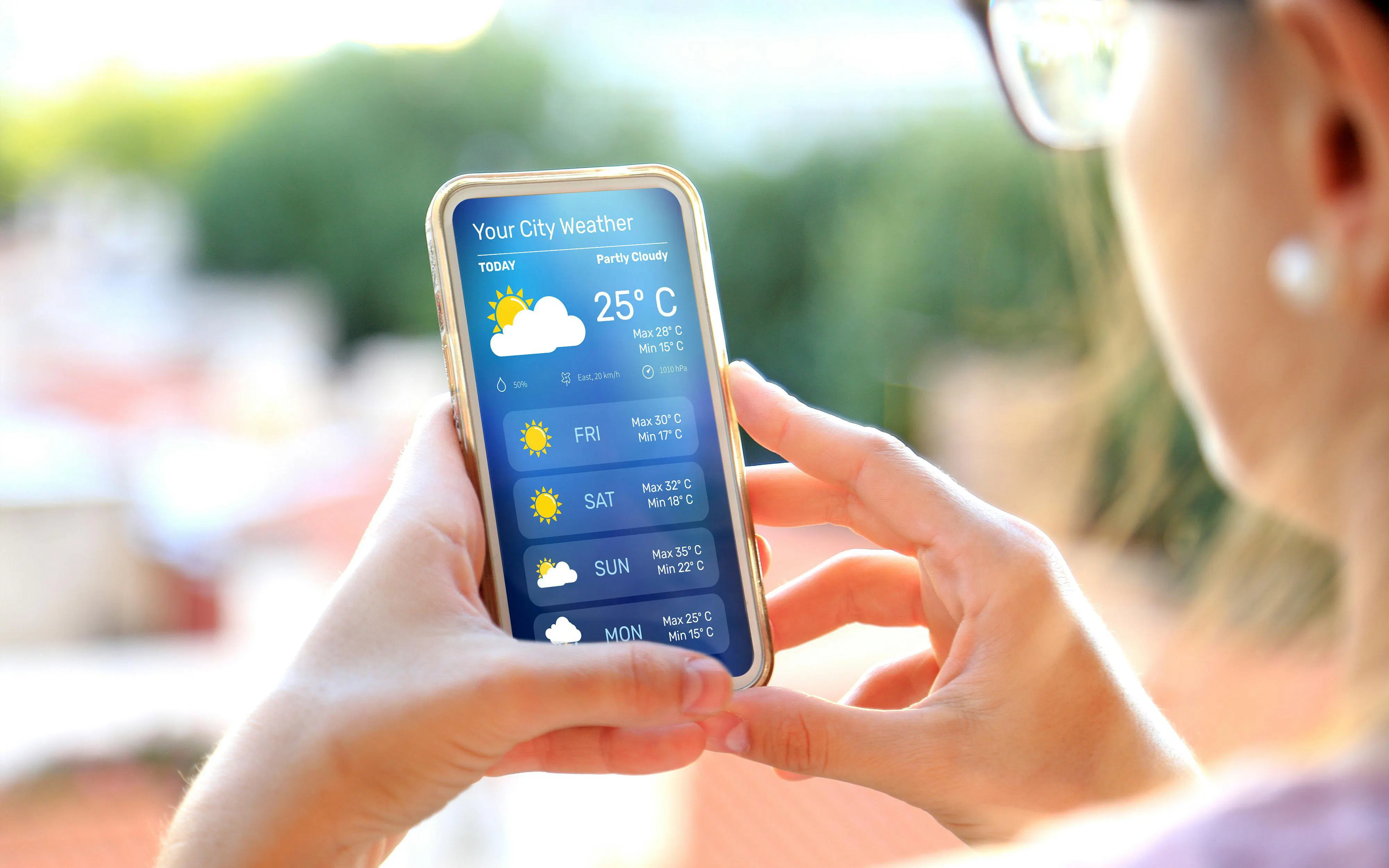 Woman checking weather forecast on smartphone outdoors in Queenstown before skydiving adventure.