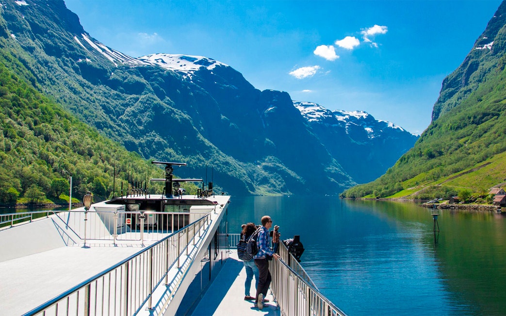 Cruise ship on Nærøyfjord with passengers enjoying scenic mountain views, Norway.