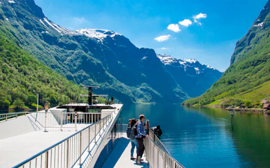 Cruise ship on Nærøyfjord with passengers enjoying scenic mountain views, Norway.