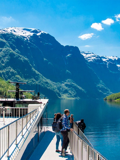Cruise ship on Nærøyfjord with passengers enjoying scenic mountain views, Norway.