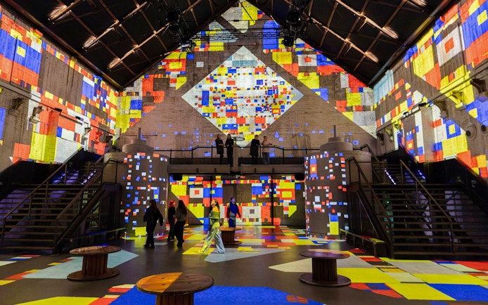 Visitors exploring colorful digital projections at Dutch Masters Exhibition, Fabrique des Lumières.