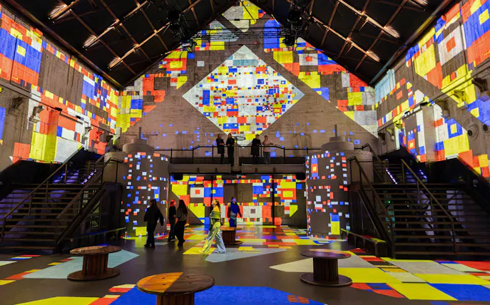 Visitors exploring colorful digital projections at Dutch Masters Exhibition, Fabrique des Lumières.