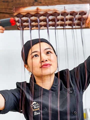 Chocolatier pouring chocolate into molds at Choco Story Brussels.