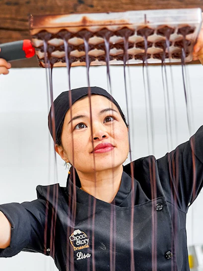 Chocolatier pouring chocolate into molds at Choco Story Brussels.