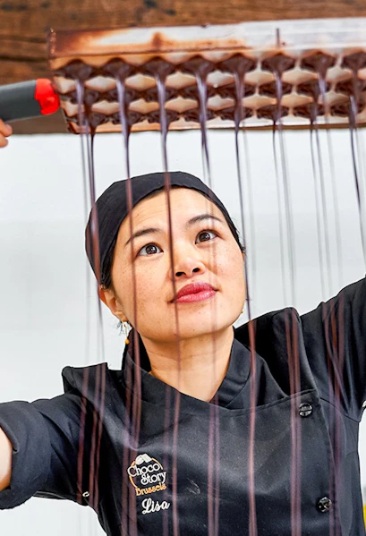 Chocolatier pouring chocolate into molds at Choco Story Brussels.